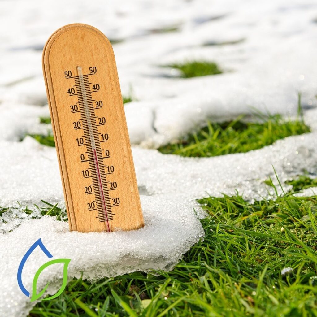 rasenfläche teilweise mit schnee bedeckt - im schnee steckt ein thermometer